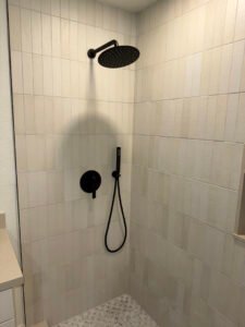 Shower valve trim and handheld shower on a tiled wall