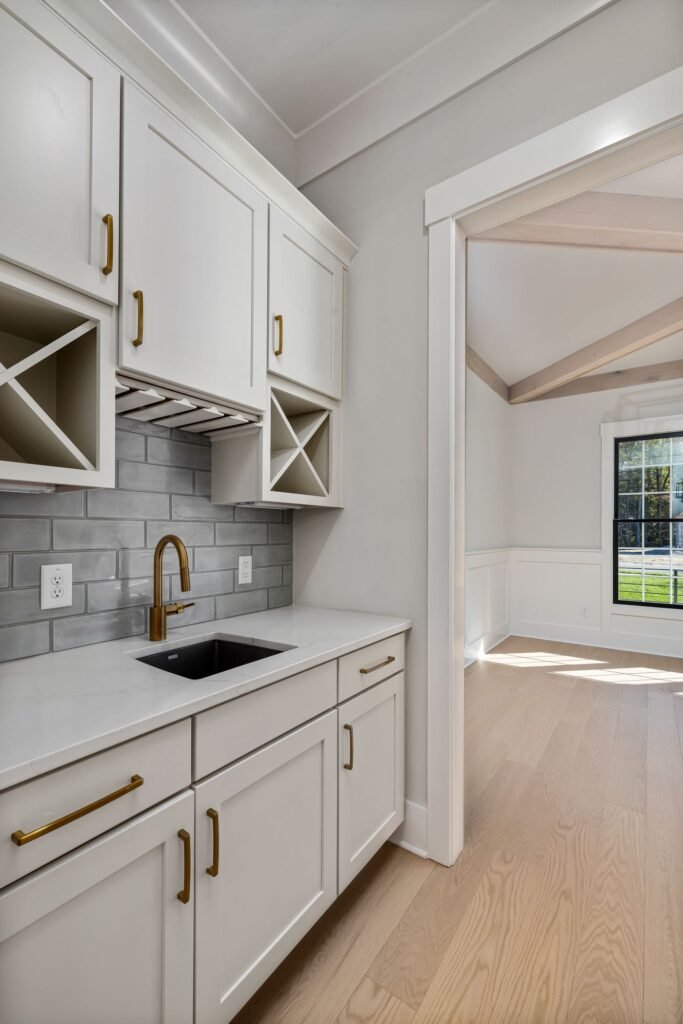 Kitchen sink with a brass faucet, white cabinetry, and natural daylight