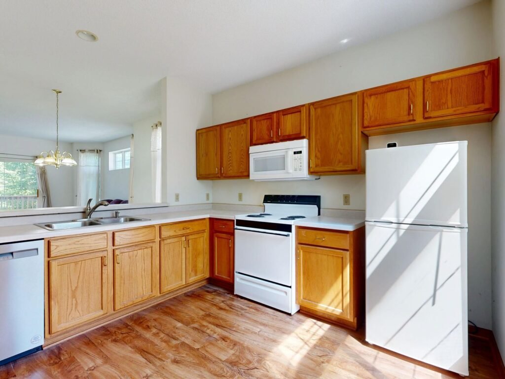 Kitchen with wood cabinets, a double sink, and sunlight through the windows
